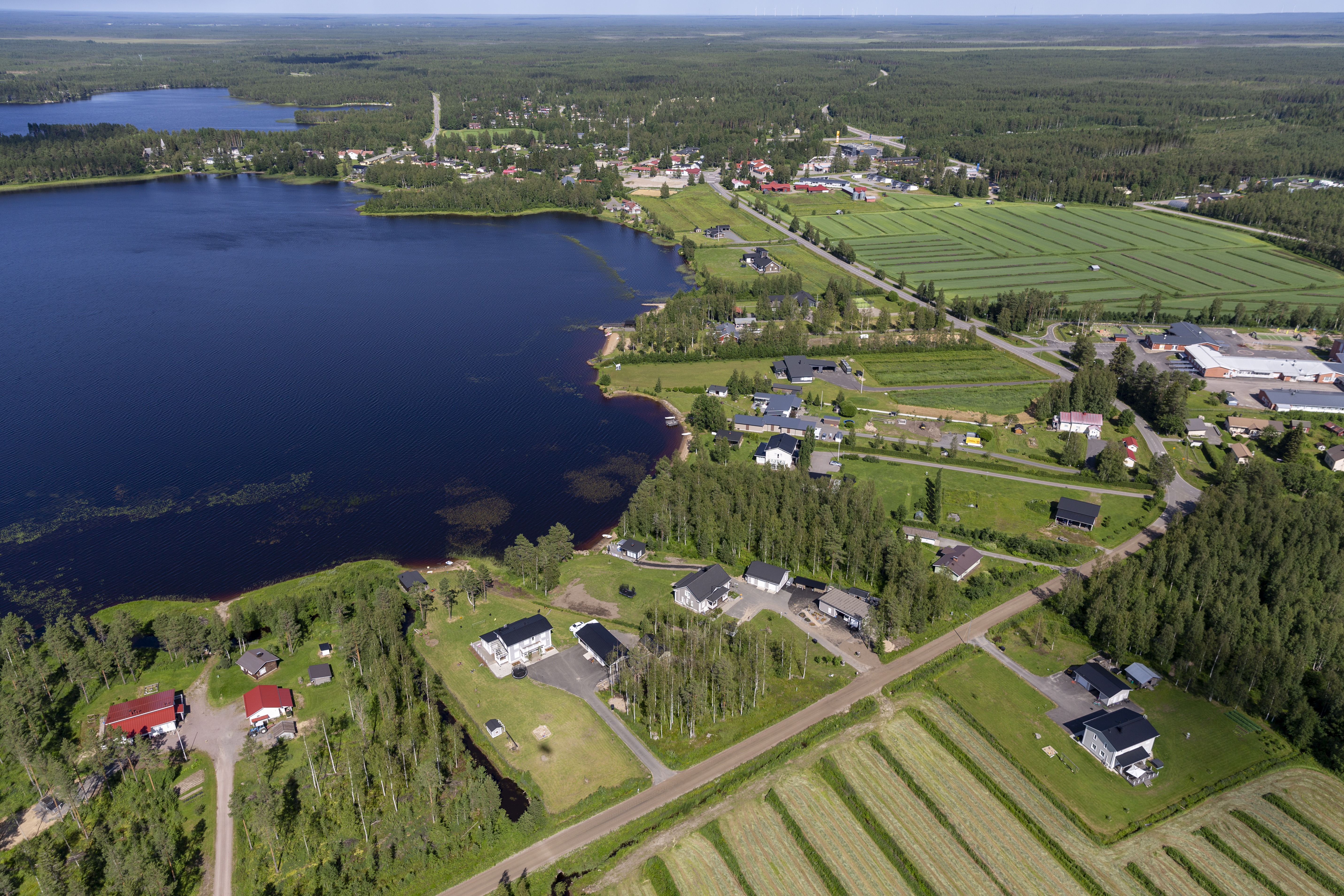 Ilmakuva, jossa taloja, järvi, peltoa